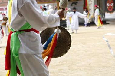 Elinde davul tutan beyaz elbiseli bir adam.