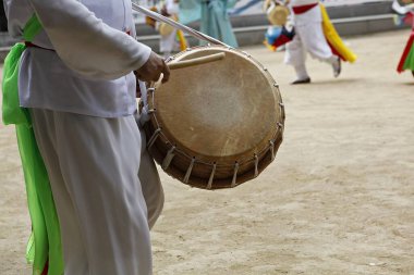 Elinde davul tutan beyaz takım elbiseli bir adam.