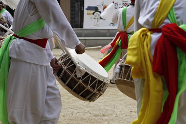 Bir grup beyaz elbiseli adam davul çalıyor.
