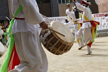 Bir grup beyaz elbiseli insan davul çalıyor.