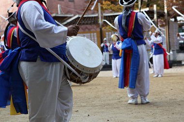 Geleneksel giyimli bir grup erkek davul çalıyor.