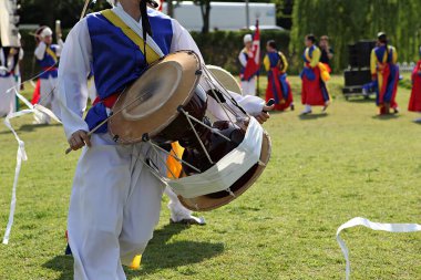 Mavi beyaz kıyafetli bir adam davul çalıyor.