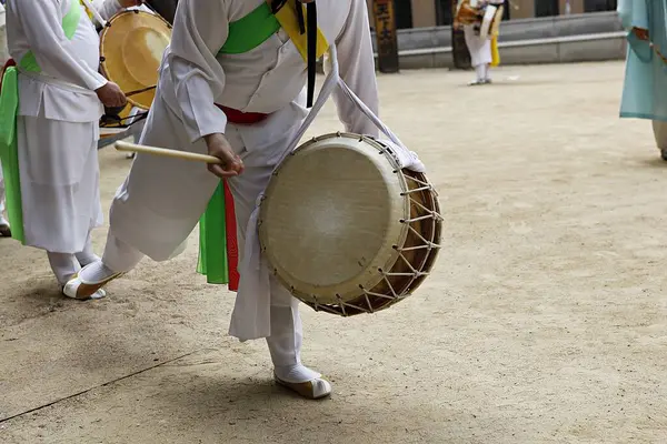 Elinde davul tutan beyaz elbiseli bir adam.