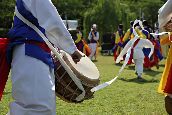 Bir grup renkli kıyafetli insan davul çalıyor.