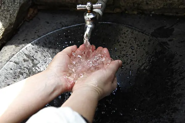 a person washing their hands with water from a faucet