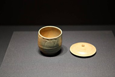 Siyah arka planda kaşıkla bir fincan çay.