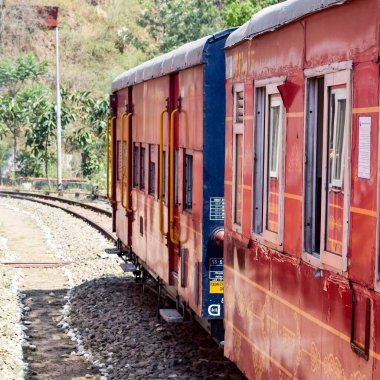 Oyuncak tren dağ yamaçlarında hareket ediyor, güzel bir manzara, bir dağ yamacı, bir vadi yamaçtan tepeye hareket ediyor, yeşil doğal ormanın arasında. Hindistan 'da Kalka' dan Shimla 'ya giden oyuncak tren, Hint treni.
