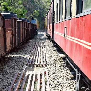 Oyuncak tren dağ yamaçlarında hareket ediyor, güzel bir manzara, bir dağ yamacı, bir vadi yamaçtan tepeye hareket ediyor, yeşil doğal ormanın arasında. Hindistan 'da Kalka' dan Shimla 'ya giden oyuncak tren, Hint treni.