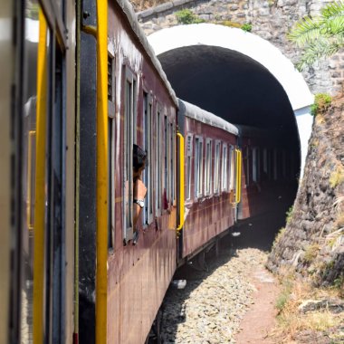 Oyuncak tren dağ yamaçlarında hareket ediyor, güzel bir manzara, bir dağ yamacı, bir vadi yamaçtan tepeye hareket ediyor, yeşil doğal ormanın arasında. Hindistan 'da Kalka' dan Shimla 'ya giden oyuncak tren, Hint treni.