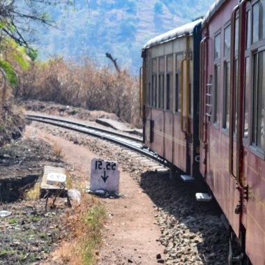 Oyuncak tren dağ yamaçlarında hareket ediyor, güzel bir manzara, bir dağ yamacı, bir vadi yamaçtan tepeye hareket ediyor, yeşil doğal ormanın arasında. Hindistan 'da Kalka' dan Shimla 'ya giden oyuncak tren, Hint treni.