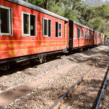 Oyuncak tren dağ yamaçlarında hareket ediyor, güzel bir manzara, bir dağ yamacı, bir vadi yamaçtan tepeye hareket ediyor, yeşil doğal ormanın arasında. Hindistan 'da Kalka' dan Shimla 'ya giden oyuncak tren, Hint treni.