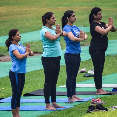 Yeni Delhi, Hindistan, 18 Haziran 2022 - Lodhi Garden 'da farklı yaşlarda insanlar için grup yoga sınıfı Surya Namaskar, Uluslararası Yoga Günü, parkta yoga dersine katılan büyük bir grup yetişkin