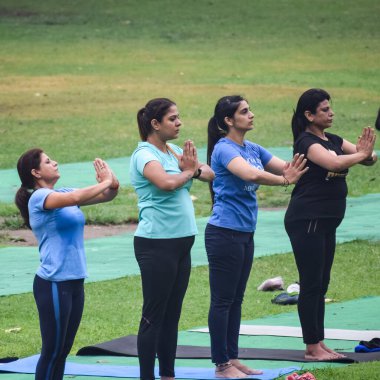 Yeni Delhi, Hindistan, 18 Haziran 2022 - Lodhi Garden 'da farklı yaşlarda insanlar için grup yoga sınıfı Surya Namaskar, Uluslararası Yoga Günü, parkta yoga dersine katılan büyük bir grup yetişkin