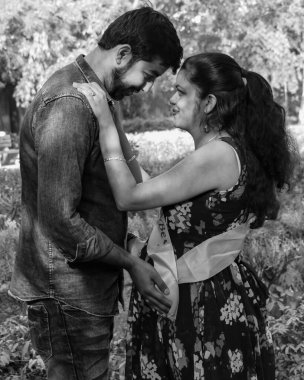 Hintli çift hamilelik çekimleri için poz veriyor. Çift yeşil çimenli bir çimenlikte poz veriyor ve kadın Yeni Delhi, Hindistan 'daki Lodhi Garden' da bebek çarpması yaşıyor.