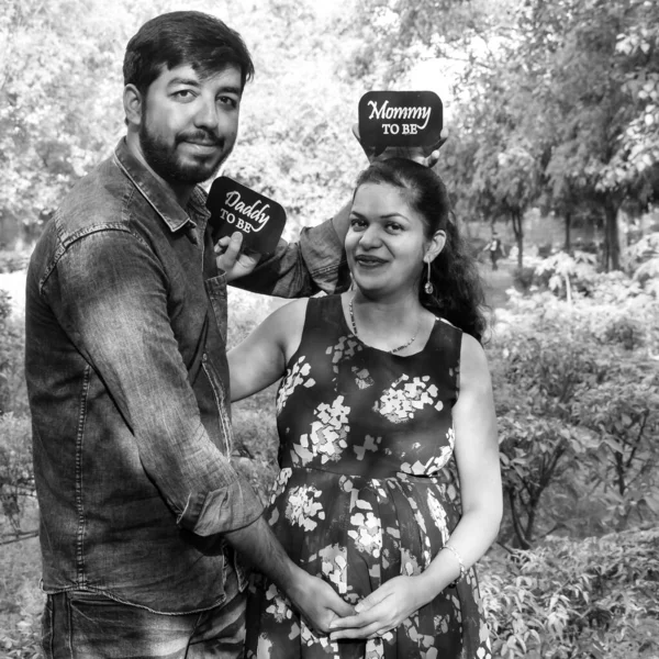 乳児撮影のためにポーズをとるインドのカップル 二人は緑の芝生の芝生の中でポーズをとっており 女性はインドのニューデリーにあるロディ ガーデンで赤ん坊のバンプを落下しています 黒と白 — ストック写真