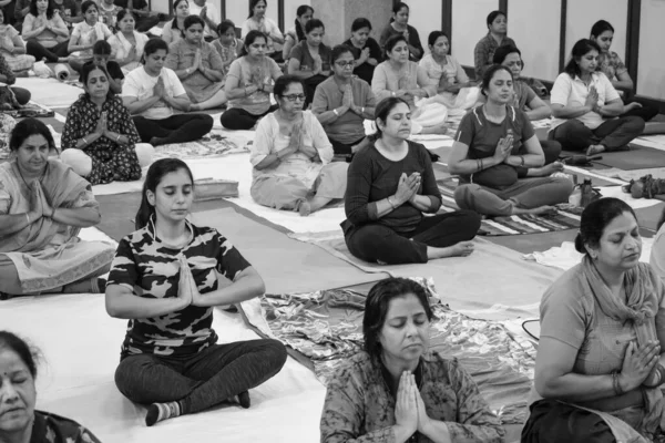 Delhi, India, June 19 2022-Group Yoga exercise session for people of different age groups in Balaji Temple,Vivek Vihar, International Yoga Day, Big group of adults attending yoga class-Black and White