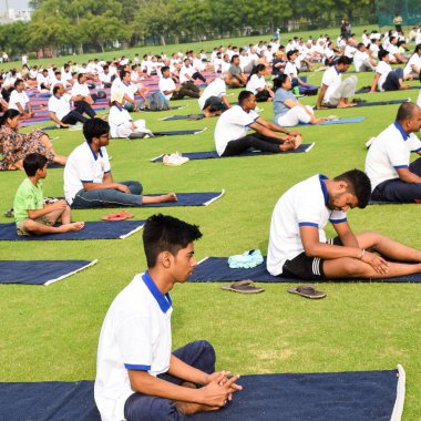 Yeni Delhi, Hindistan, 21 Haziran 2022 - Uluslararası Yoga Günü 'nde Delhi' deki Yamuna Spor Kompleksi 'nde grup Yoga egzersiz oturumu, kriket stadyumunda yoga derslerine katılan büyük bir grup yetişkin