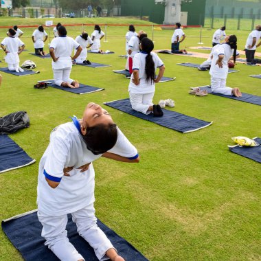 Yeni Delhi, Hindistan, 21 Haziran 2022 - Uluslararası Yoga Günü 'nde Delhi' deki Yamuna Spor Kompleksi 'nde grup Yoga egzersiz oturumu, kriket stadyumunda yoga derslerine katılan büyük bir grup yetişkin