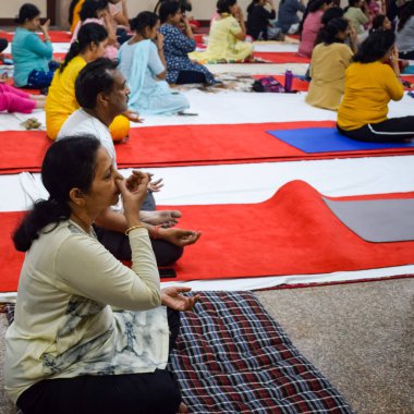 New Delhi, India, June 19 2022 -Group Yoga exercise session for people of different age groups in Balaji Temple, Vivek Vihar, International Yoga Day, Big group of adults attending yoga class in temple