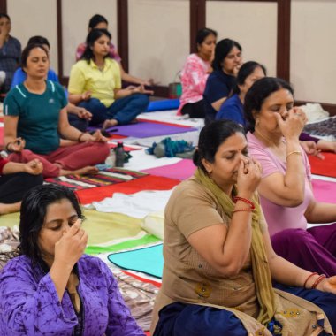 New Delhi, India, June 19 2022 -Group Yoga exercise session for people of different age groups in Balaji Temple, Vivek Vihar, International Yoga Day, Big group of adults attending yoga class in temple