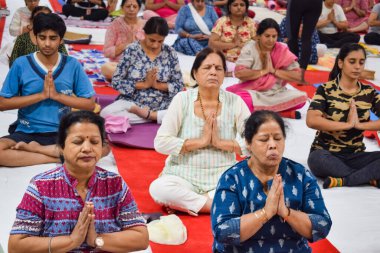 New Delhi, India, June 19 2022 -Group Yoga exercise session for people of different age groups in Balaji Temple, Vivek Vihar, International Yoga Day, Big group of adults attending yoga class in temple