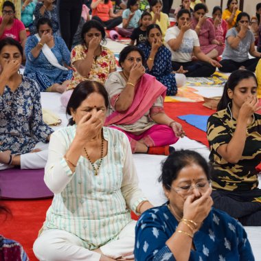 New Delhi, India, June 19 2022 -Group Yoga exercise session for people of different age groups in Balaji Temple, Vivek Vihar, International Yoga Day, Big group of adults attending yoga class in temple