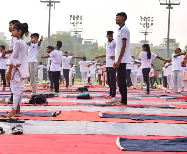 Yeni Delhi, Hindistan, 21 Haziran 2022 - Uluslararası Yoga Günü 'nde Delhi' deki Yamuna Spor Kompleksi 'nde grup Yoga egzersiz oturumu, kriket stadyumunda yoga derslerine katılan büyük bir grup yetişkin