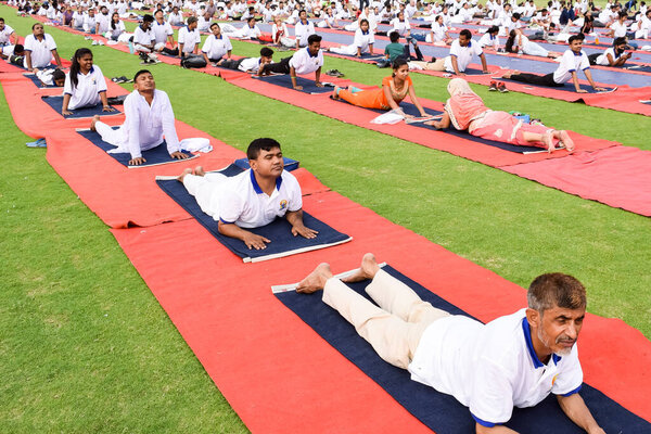 New Delhi, India, June 21 2022 - Group Yoga exercise session for people at Yamuna Sports Complex in Delhi on International Yoga Day, Big group of adults attending yoga class in cricket stadium