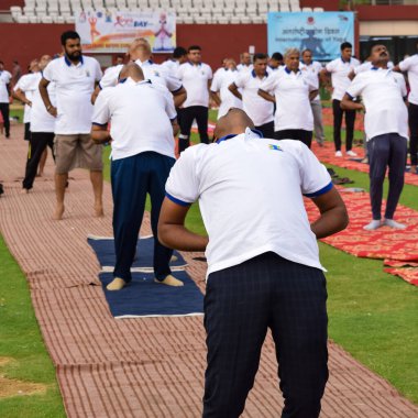 Yeni Delhi, Hindistan, 21 Haziran 2022 - Uluslararası Yoga Günü 'nde Delhi' deki Yamuna Spor Kompleksi 'nde grup Yoga egzersiz oturumu, kriket stadyumunda yoga derslerine katılan büyük bir grup yetişkin