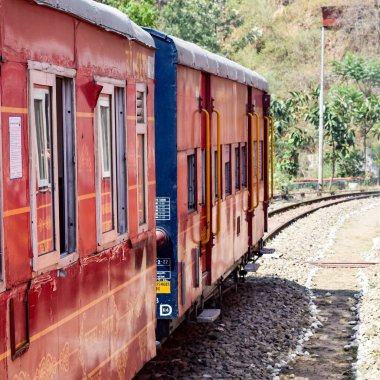 Oyuncak tren dağ yamaçlarında hareket ediyor, güzel bir manzara, bir dağ yamacı, bir vadi yamaçtan tepeye hareket ediyor, yeşil doğal ormanın arasında. Hindistan 'da Kalka' dan Shimla 'ya giden oyuncak tren, Hint treni.