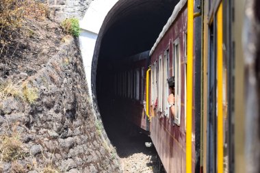 Oyuncak tren dağ yamaçlarında hareket ediyor, güzel bir manzara, bir dağ yamacı, bir vadi yamaçtan tepeye hareket ediyor, yeşil doğal ormanın arasında. Hindistan 'da Kalka' dan Shimla 'ya giden oyuncak tren, Hint treni.