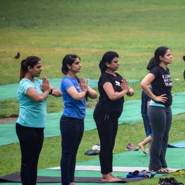 Yeni Delhi, Hindistan, 18 Haziran 2022 - Lodhi Garden 'da farklı yaşlarda insanlar için grup yoga sınıfı Surya Namaskar, Uluslararası Yoga Günü, parkta yoga dersine katılan büyük bir grup yetişkin