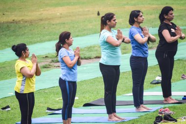 Yeni Delhi, Hindistan, 18 Haziran 2022 - Lodhi Garden 'da farklı yaşlarda insanlar için grup yoga sınıfı Surya Namaskar, Uluslararası Yoga Günü, parkta yoga dersine katılan büyük bir grup yetişkin