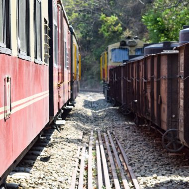 Oyuncak tren dağ yamaçlarında hareket ediyor, güzel bir manzara, bir dağ yamacı, bir vadi yamaçtan tepeye hareket ediyor, yeşil doğal ormanın arasında. Hindistan 'da Kalka' dan Shimla 'ya giden oyuncak tren, Hint treni.