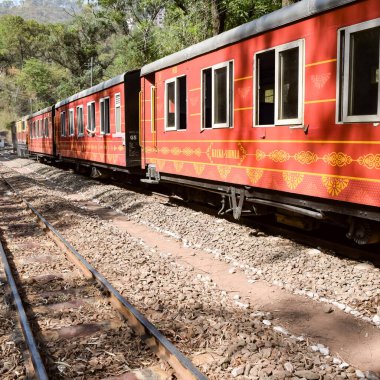 Oyuncak tren dağ yamaçlarında hareket ediyor, güzel bir manzara, bir dağ yamacı, bir vadi yamaçtan tepeye hareket ediyor, yeşil doğal ormanın arasında. Hindistan 'da Kalka' dan Shimla 'ya giden oyuncak tren, Hint treni.