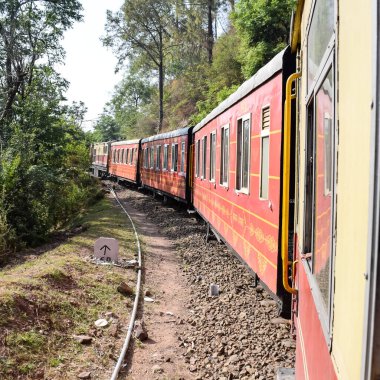 Toy Train moving on mountain slopes, beautiful view, one side mountain, one side valley moving on railway to the hill, among green natural forest. Toy train from Kalka to Shimla in India, Indian Train