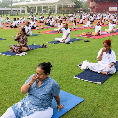 Yeni Delhi, Hindistan, 21 Haziran 2022 - Uluslararası Yoga Günü 'nde Delhi' deki Yamuna Spor Kompleksi 'nde grup Yoga egzersiz oturumu, kriket stadyumunda yoga derslerine katılan büyük bir grup yetişkin