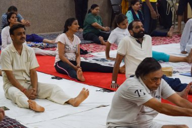 New Delhi, India, June 19 2022 -Group Yoga exercise session for people of different age groups in Balaji Temple, Vivek Vihar, International Yoga Day, Big group of adults attending yoga class in temple