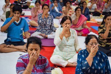 New Delhi, India, June 19 2022 -Group Yoga exercise session for people of different age groups in Balaji Temple, Vivek Vihar, International Yoga Day, Big group of adults attending yoga class in temple