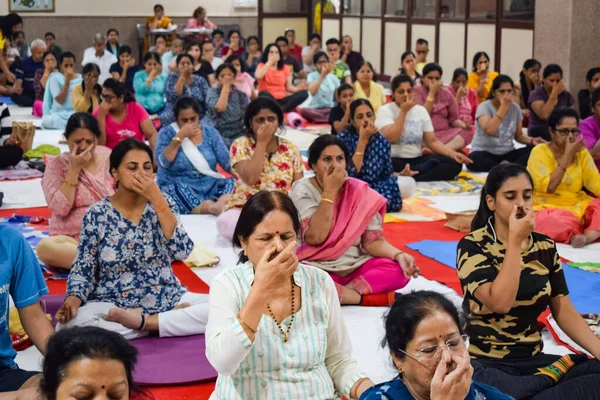 New Delhi, India, June 19 2022 -Group Yoga exercise session for people of different age groups in Balaji Temple, Vivek Vihar, International Yoga Day, Big group of adults attending yoga class in temple