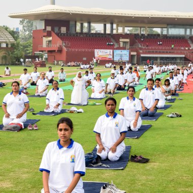 Yeni Delhi, Hindistan, 21 Haziran 2022 - Uluslararası Yoga Günü 'nde Delhi' deki Yamuna Spor Kompleksi 'nde grup Yoga egzersiz oturumu, kriket stadyumunda yoga derslerine katılan büyük bir grup yetişkin