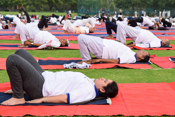 New Delhi, India, June 21 2022 - Group Yoga exercise session for people at Yamuna Sports Complex in Delhi on International Yoga Day, Big group of adults attending yoga class in cricket stadium