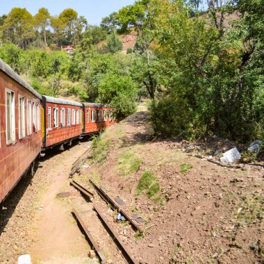 Oyuncak tren dağ yamaçlarında hareket ediyor, güzel bir manzara, bir dağ yamacı, bir vadi yamaçtan tepeye hareket ediyor, yeşil doğal ormanın arasında. Hindistan 'da Kalka' dan Shimla 'ya giden oyuncak tren, Hint treni.