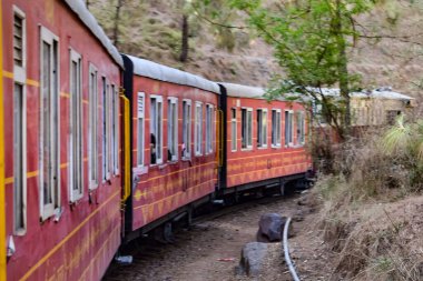 Toy Train moving on mountain slopes, beautiful view, one side mountain, one side valley moving on railway to the hill, among green natural forest. Toy train from Kalka to Shimla in India, Indian Train
