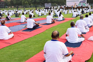 Yeni Delhi, Hindistan, 21 Haziran 2022 - Uluslararası Yoga Günü 'nde Delhi' deki Yamuna Spor Kompleksi 'nde grup Yoga egzersiz oturumu, kriket stadyumunda yoga derslerine katılan büyük bir grup yetişkin