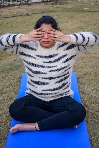 Young Indian woman practicing yoga outdoor in a park. Beautiful girl practice basic yoga pose. Calmness and relax, female happiness. Basic Yoga Exercise outdoor