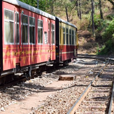 Oyuncak tren dağ yamaçlarında hareket ediyor, güzel bir manzara, bir dağ yamacı, bir vadi yamaçtan tepeye hareket ediyor, yeşil doğal ormanın arasında. Hindistan 'da Kalka' dan Shimla 'ya giden oyuncak tren, Hint treni.