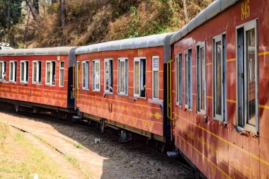 Oyuncak tren dağ yamaçlarında hareket ediyor, güzel bir manzara, bir dağ yamacı, bir vadi yamaçtan tepeye hareket ediyor, yeşil doğal ormanın arasında. Hindistan 'da Kalka' dan Shimla 'ya giden oyuncak tren, Hint treni.