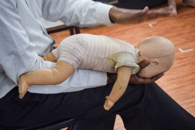 Man performing CPR on baby training doll dummy with one hand compression. First Aid Training - Cardiopulmonary resuscitation. First aid course on CPR dummy, CPR First Aid Training Concept