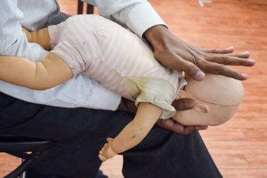 Man performing CPR on baby training doll dummy with one hand compression. First Aid Training - Cardiopulmonary resuscitation. First aid course on CPR dummy, CPR First Aid Training Concept